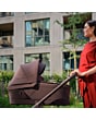 1518084110_F8_2026_maxicosi_stroller_oxfordcarrycot_espressobrown_lifestyle_momcheckingcarrycotside